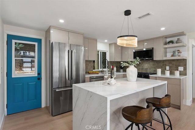 kitchen with appliances with stainless steel finishes, light hardwood / wood-style floors, pendant lighting, gray cabinets, and a kitchen island