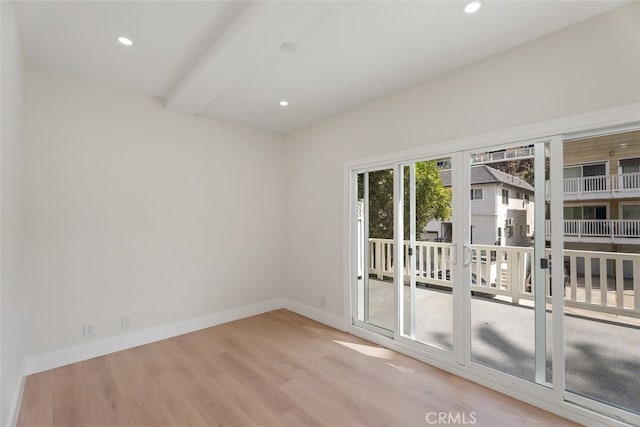 unfurnished room featuring beamed ceiling and light wood-type flooring