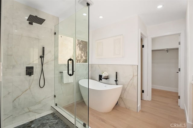 bathroom with hardwood / wood-style floors, independent shower and bath, and tile walls