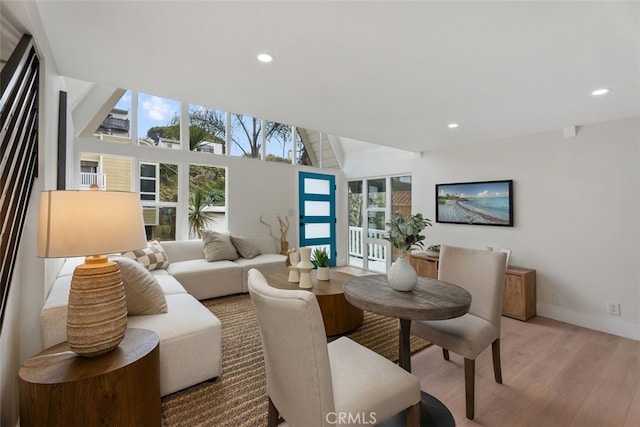 living room featuring lofted ceiling, a healthy amount of sunlight, and light hardwood / wood-style floors