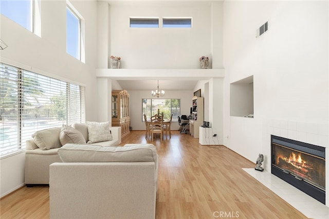 living room with a towering ceiling, plenty of natural light, and light hardwood / wood-style floors