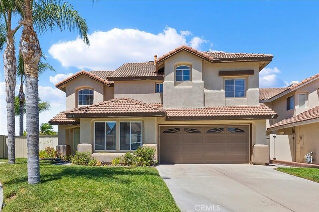 mediterranean / spanish home featuring a front yard and a garage