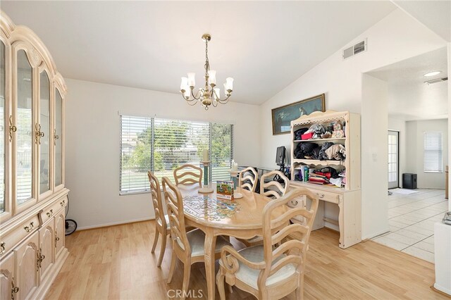 dining room featuring a notable chandelier, lofted ceiling, and light wood-type flooring