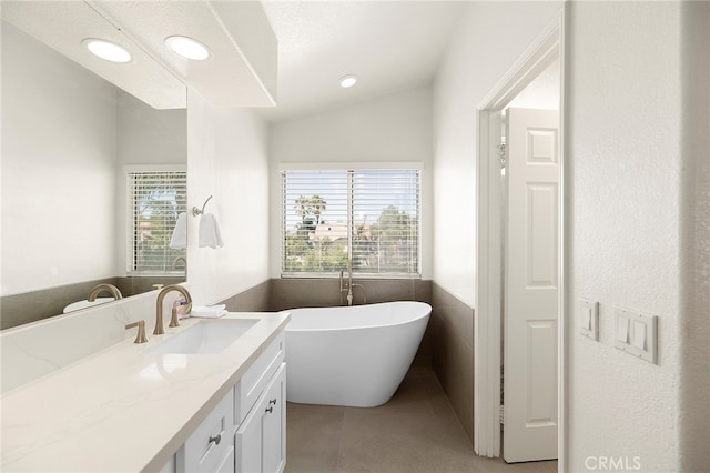 bathroom with tile patterned floors, a tub to relax in, vaulted ceiling, vanity, and a textured ceiling