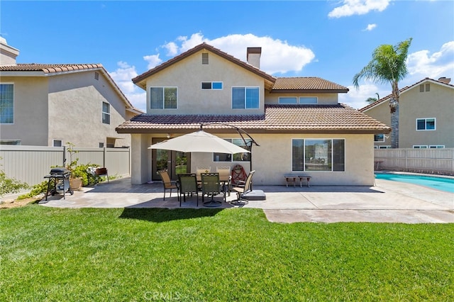 rear view of house featuring a yard, a patio area, and a fenced in pool