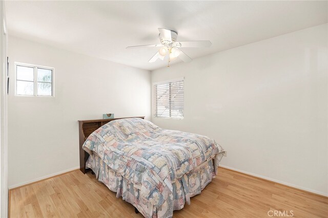 bedroom with multiple windows, light hardwood / wood-style floors, and ceiling fan