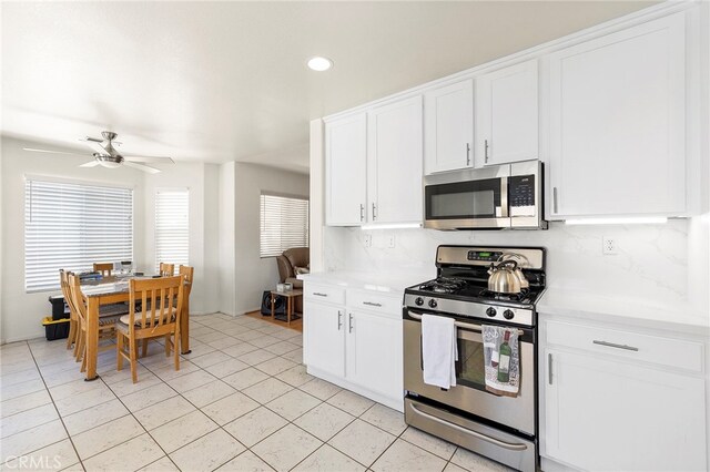 kitchen with decorative backsplash, light tile patterned floors, ceiling fan, white cabinetry, and stainless steel appliances