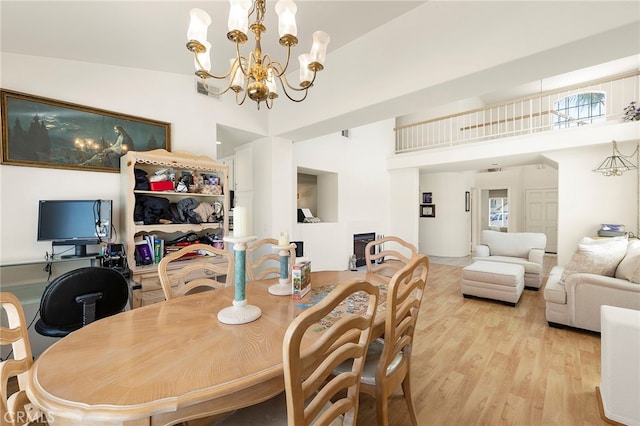 dining space featuring light hardwood / wood-style floors, a chandelier, and high vaulted ceiling