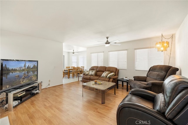 living room with light hardwood / wood-style floors and ceiling fan with notable chandelier