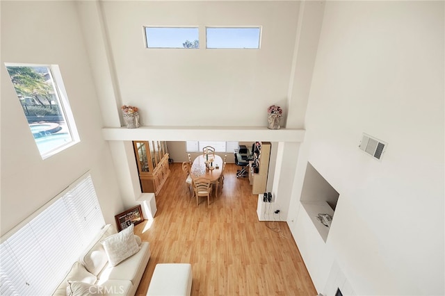 living room with light hardwood / wood-style flooring and a high ceiling