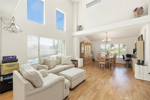 living room featuring a towering ceiling, a notable chandelier, and light wood-type flooring