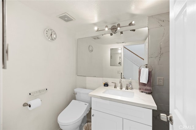 bathroom featuring vanity, a textured ceiling, and toilet