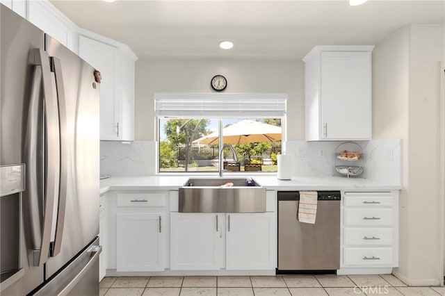 kitchen featuring sink, white cabinets, light tile patterned floors, appliances with stainless steel finishes, and tasteful backsplash