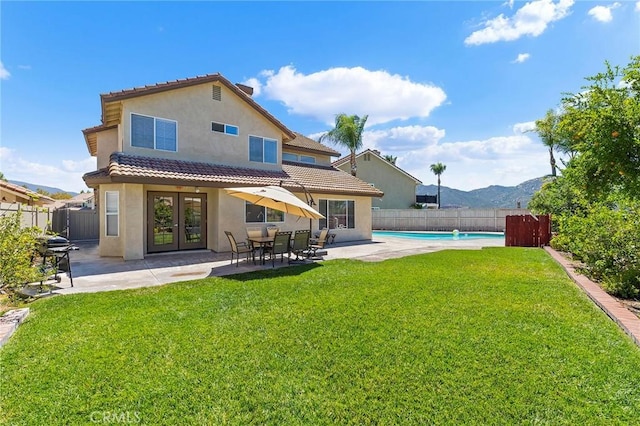 back of property featuring a lawn, french doors, stucco siding, a fenced backyard, and a patio area