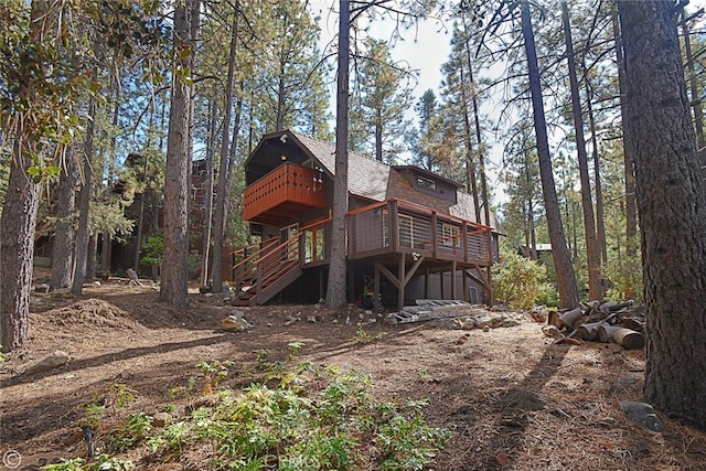 rear view of house with a shingled roof, stairway, and a deck