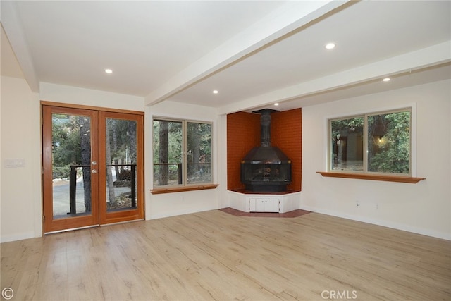 unfurnished living room featuring french doors, beam ceiling, recessed lighting, a wood stove, and wood finished floors