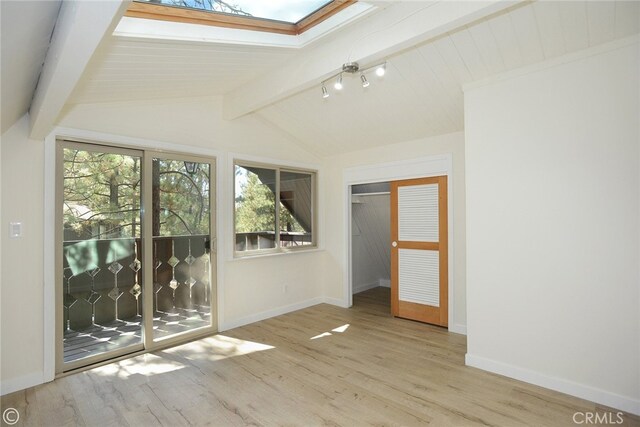 unfurnished bedroom featuring access to exterior, vaulted ceiling with skylight, wood finished floors, and baseboards