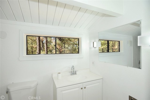 half bath with lofted ceiling, vanity, and toilet