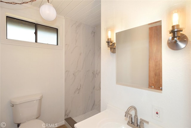 full bathroom featuring tiled shower, a sink, and toilet