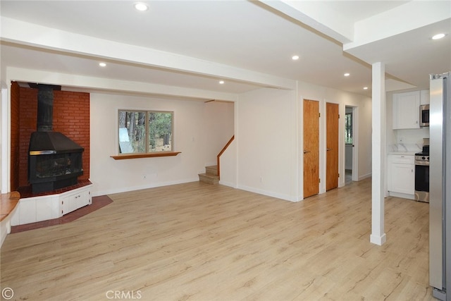 unfurnished living room featuring light wood-style flooring, recessed lighting, stairs, beamed ceiling, and a wood stove