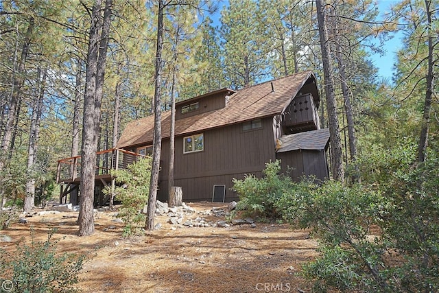 view of home's exterior featuring a wooded view and a wooden deck