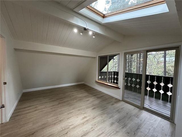 unfurnished room with vaulted ceiling with skylight, baseboards, and wood finished floors