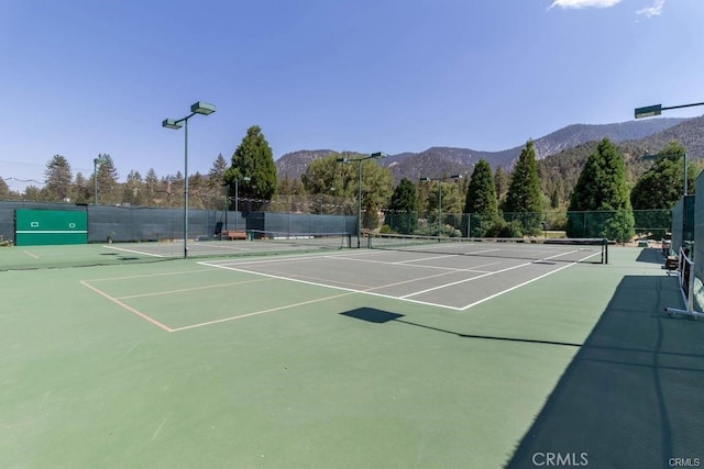 view of sport court with fence and a mountain view