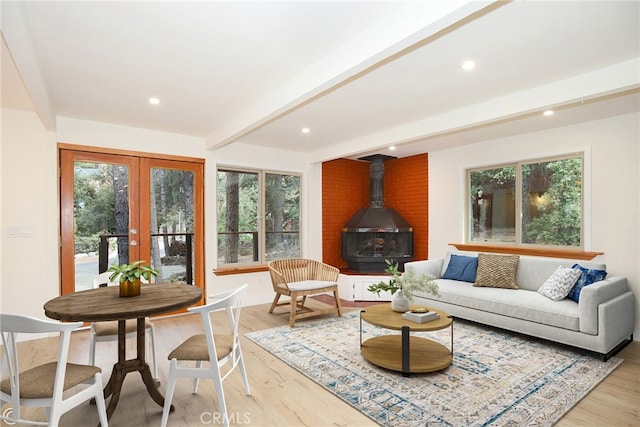 living area featuring light wood-style flooring, recessed lighting, french doors, beam ceiling, and a wood stove