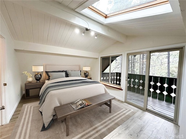 bedroom featuring light wood-type flooring, lofted ceiling with skylight, baseboards, and access to exterior