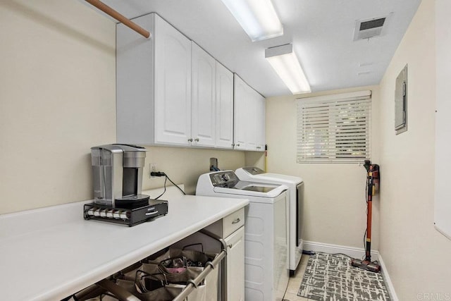 laundry area featuring cabinets, light tile patterned floors, electric panel, and washing machine and clothes dryer