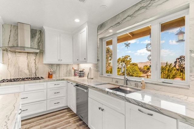 kitchen with white cabinets, sink, wall chimney exhaust hood, and appliances with stainless steel finishes