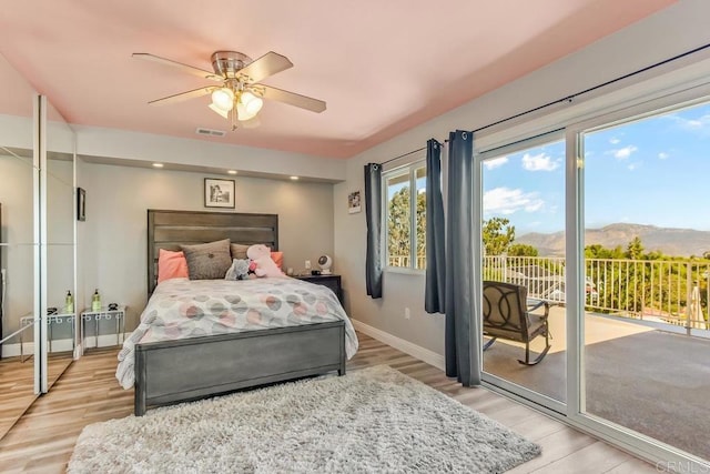 bedroom featuring a mountain view, ceiling fan, light wood-type flooring, and access to outside