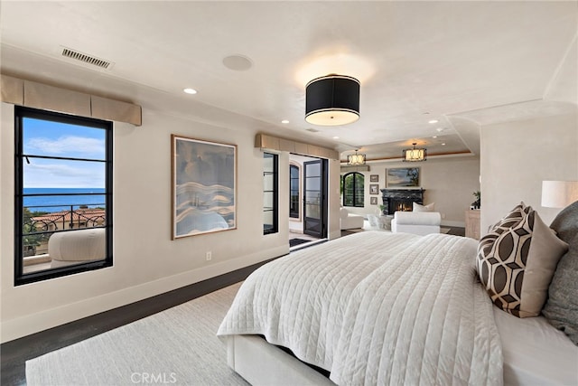 bedroom featuring a water view and dark hardwood / wood-style flooring