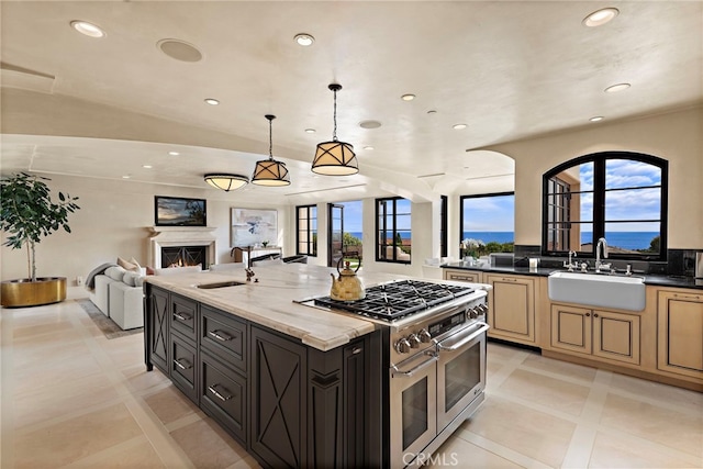 kitchen featuring pendant lighting, double oven range, dark stone countertops, and sink