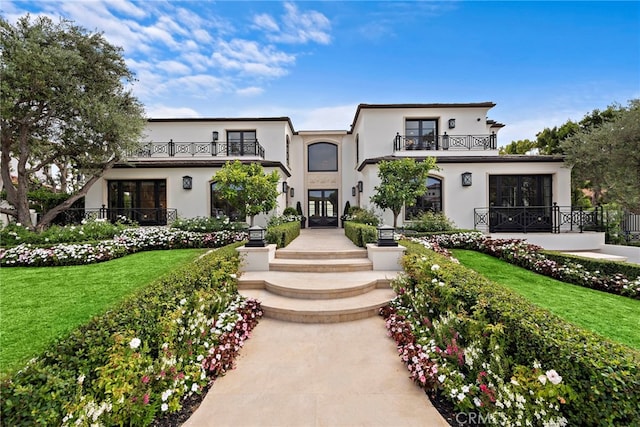 view of front of house with a front yard and a balcony