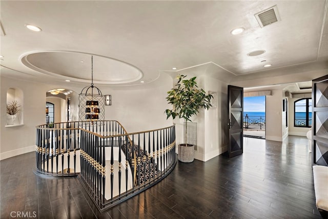 hall with a water view, dark hardwood / wood-style floors, and a tray ceiling