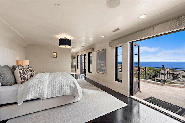 bedroom featuring wood-type flooring and a water view