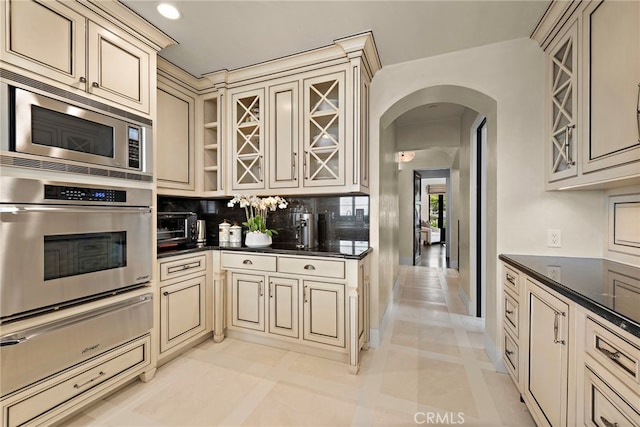 kitchen featuring appliances with stainless steel finishes, cream cabinets, light tile patterned flooring, and tasteful backsplash