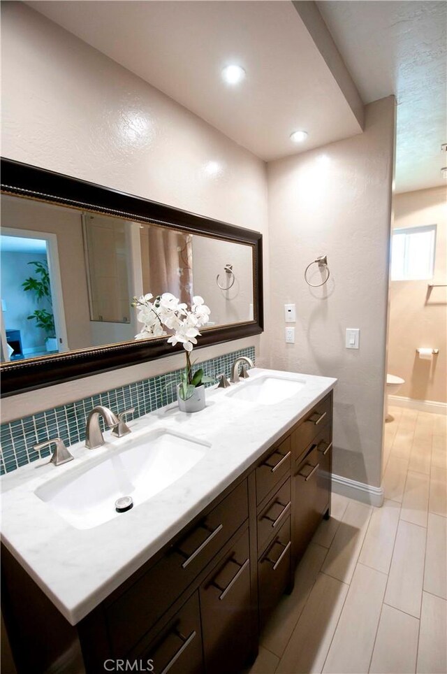 bathroom with backsplash, vanity, and toilet