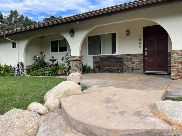 property entrance featuring a porch and a yard