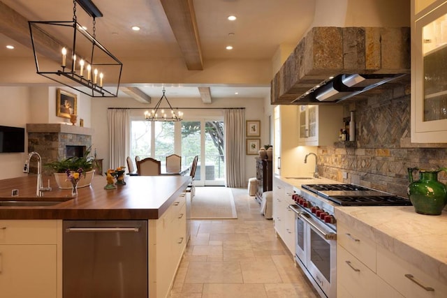 kitchen featuring appliances with stainless steel finishes, white cabinets, beamed ceiling, sink, and butcher block countertops