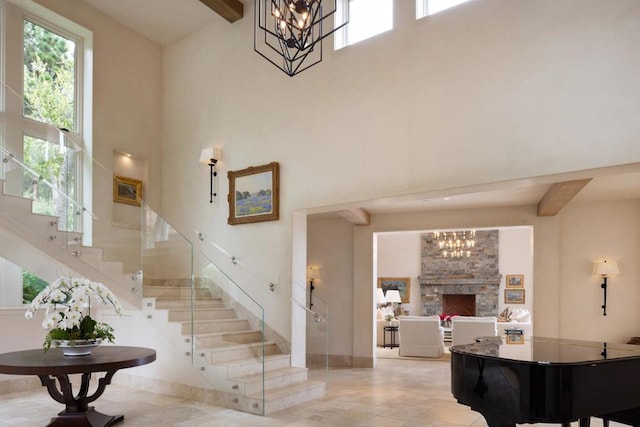 entryway with an inviting chandelier, beam ceiling, a fireplace, and a high ceiling