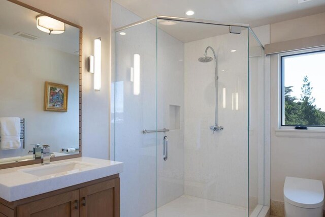 bathroom featuring toilet, walk in shower, and vanity