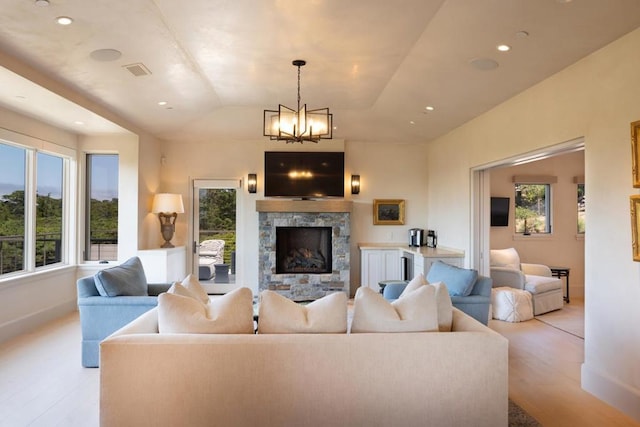 living room with light wood-type flooring, lofted ceiling, a healthy amount of sunlight, and a fireplace