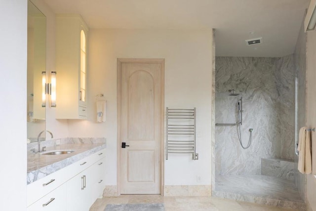 bathroom with vanity, tile patterned floors, radiator heating unit, and tiled shower