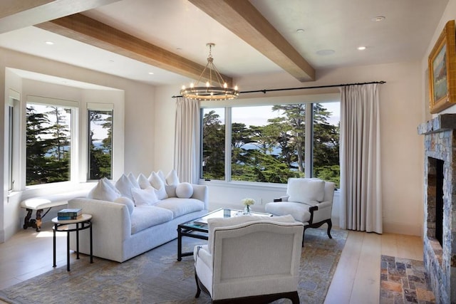 living room with beam ceiling, a notable chandelier, a stone fireplace, and hardwood / wood-style floors