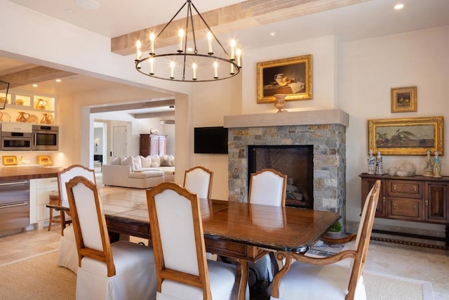 dining space featuring beam ceiling, a notable chandelier, and a fireplace