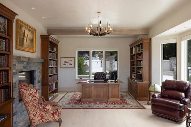 office with light hardwood / wood-style flooring, a notable chandelier, and a fireplace