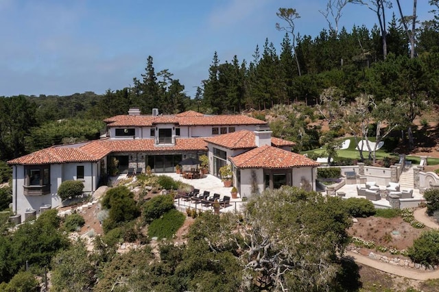 back of house with an outdoor living space and a patio