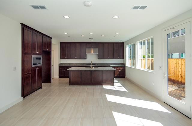 kitchen featuring sink, dark brown cabinetry, and a kitchen island with sink